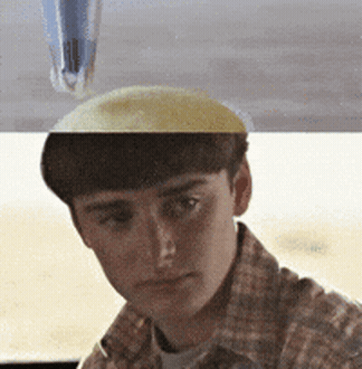 A Man In A Plaid Shirt Is Looking At The Camera With A Pen On His Head GIF