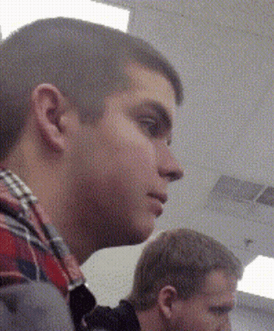 A Man In A Plaid Shirt Is Looking To His Left GIF