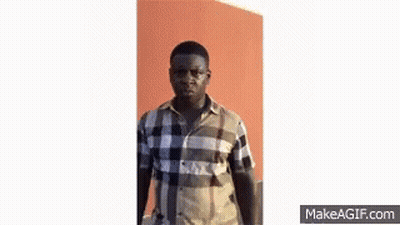 A Man In A Plaid Shirt Is Making A Funny Face And Looking At The Camera . GIF