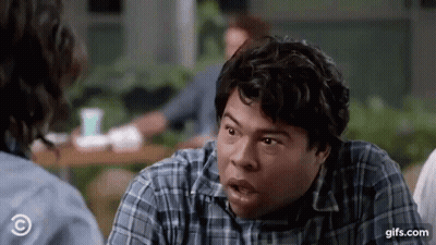 A Man In A Plaid Shirt Is Making A Funny Face While Talking To A Woman . GIF