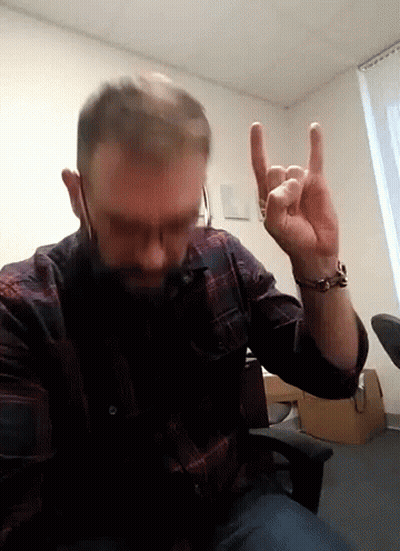 A Man In A Plaid Shirt Is Making A Horns Sign With His Fingers GIF