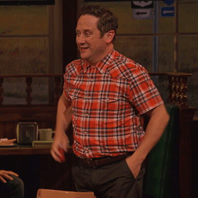A Man In A Plaid Shirt Is Sitting At A Table With A Sign That Says U On It GIF
