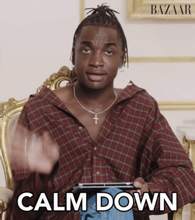 A Man In A Plaid Shirt Is Sitting In A Chair And Holding A Tablet With The Words Calm Down Written On It GIF