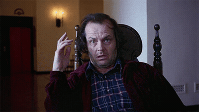 A Man In A Plaid Shirt Is Sitting In A Chair And Making A Funny Face GIF
