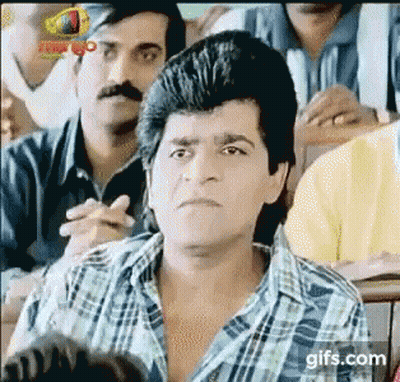 A Man In A Plaid Shirt Is Sitting In Front Of A Group Of People . GIF