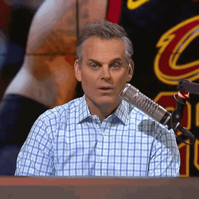 a man in a plaid shirt is sitting in front of a microphone with a cleveland cavaliers jersey in the background