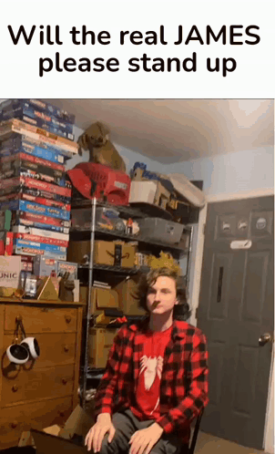 A Man In A Plaid Shirt Is Sitting In Front Of A Stack Of Board Games And A Sign That Says Will The Real James GIF