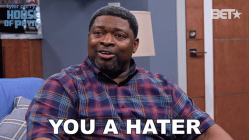 A Man In A Plaid Shirt Is Sitting On A Blue Couch And Says " You A Hater " GIF
