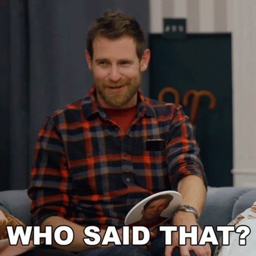 A Man In A Plaid Shirt Is Sitting On A Couch And Holding A Picture Of A Man And Says Who Said That GIF