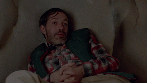 A Man In A Plaid Shirt Is Sitting On A Couch With His Head Resting On His Hands And The Words My Art Above Him GIF