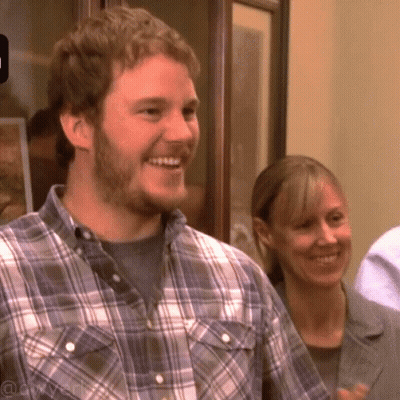 A Man In A Plaid Shirt Is Smiling While A Woman Looks On GIF