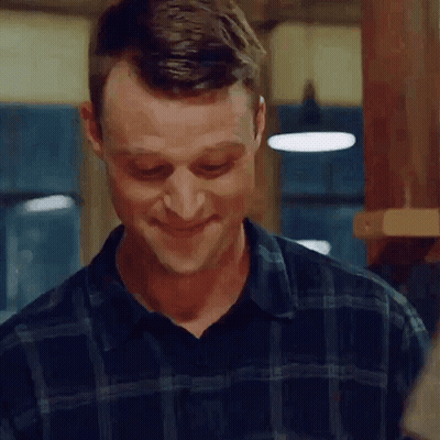 a man in a plaid shirt is smiling while standing in a kitchen .