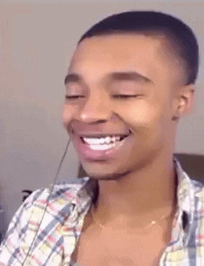 A Man In A Plaid Shirt Is Smiling With His Eyes Closed GIF