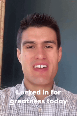 A Man In A Plaid Shirt Is Smiling With The Words " Locked In For Greatness Today " Below Him GIF