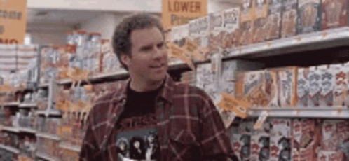 A Man In A Plaid Shirt Is Standing In A Grocery Store Looking At Cereal . GIF