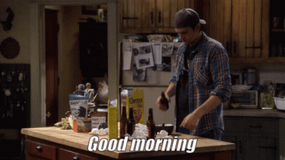 A Man In A Plaid Shirt Is Standing In A Kitchen With A Box Of Cheerios On The Counter GIF