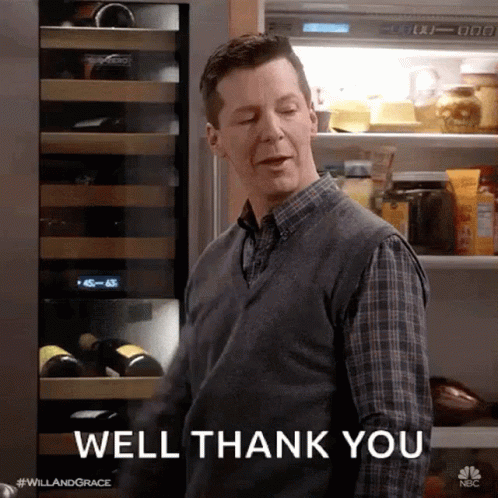A Man In A Plaid Shirt Is Standing In Front Of A Refrigerator And Saying Well Thank You . GIF