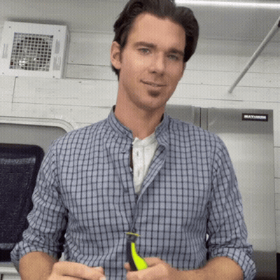 A Man In A Plaid Shirt Is Standing In Front Of A Stainless Steel Refrigerator That Says Maximum GIF
