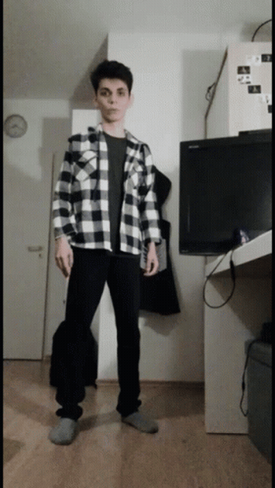 A Man In A Plaid Shirt Is Standing In Front Of A Television GIF