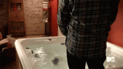 A Man In A Plaid Shirt Is Standing Next To A Hot Tub That Says Mtv GIF