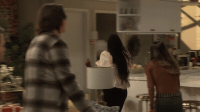 A Man In A Plaid Shirt Is Standing Next To A Woman Holding A White Lamp Shade GIF