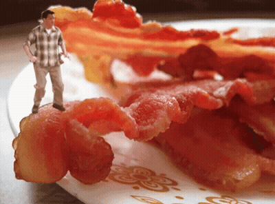 A Man In A Plaid Shirt Is Standing On Top Of A Plate Of Bacon GIF
