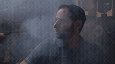 A Man In A Plaid Shirt Is Surrounded By Smoke And A Sign That Says ' A ' On It GIF