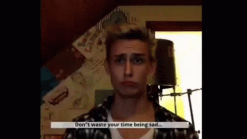 A Man In A Plaid Shirt Is Talking Into A Microphone And Says `` Don 'T Waste Your Time Being Sad ... '' GIF