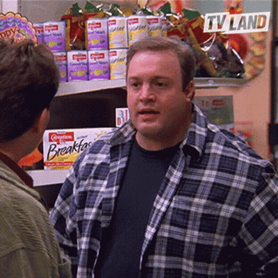 A Man In A Plaid Shirt Is Talking To Another Man In A Grocery Store With A Sign That Says Tv Land GIF