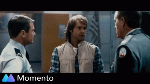 A Man In A Plaid Shirt Is Talking To Two Police Officers In A Momento Advertisement GIF