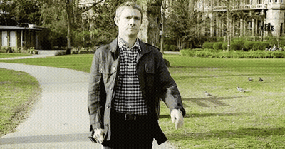 A Man In A Plaid Shirt Is Walking Through A Park . GIF
