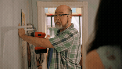 A Man In A Plaid Shirt Is Working On A Wall GIF