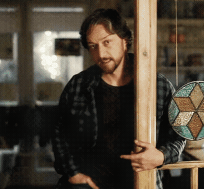 A Man In A Plaid Shirt Leans Against A Wooden Pole GIF