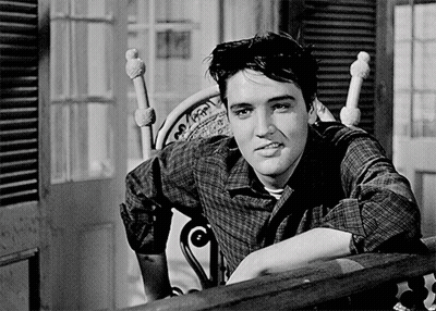 A Man In A Plaid Shirt Leans On A Railing GIF