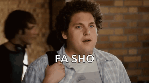 A Man In A Plaid Shirt Says Fa Sho In Front Of A Brick Wall GIF