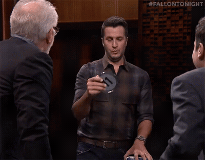 A Man In A Plaid Shirt Says Ruh Roh In Front Of A Group Of Men GIF