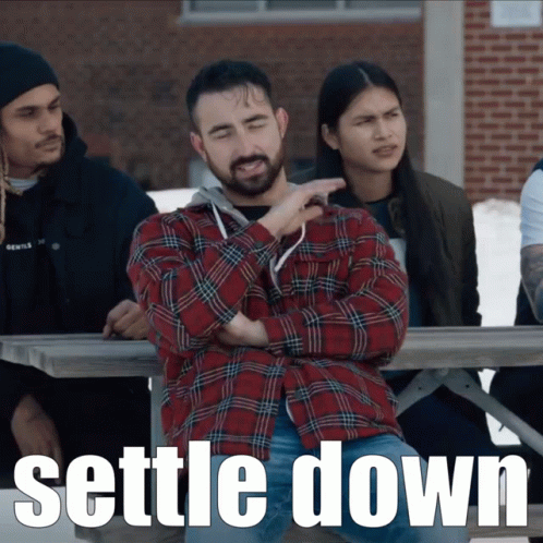 A Man In A Plaid Shirt Sits At A Picnic Table With The Words " Settle Down " On The Bottom GIF
