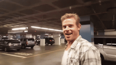 A Man In A Plaid Shirt Stands In A Parking Garage With A Stop Sign On The Ground GIF