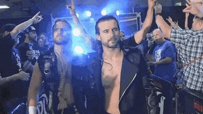 A Man In A Plaid Shirt Stands In Front Of A Crowd With The Number 91 On The Back GIF