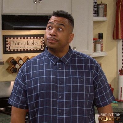 A Man In A Plaid Shirt Stands In Front Of A Sign That Says " Family Table " GIF