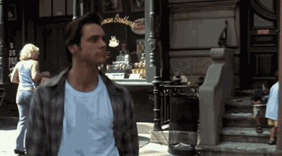 A Man In A Plaid Shirt Stands In Front Of A Store Called Man Brothers GIF