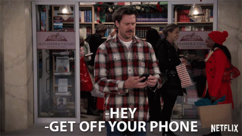 A Man In A Plaid Shirt Stands In Front Of An Alexander & Vaughn Store GIF