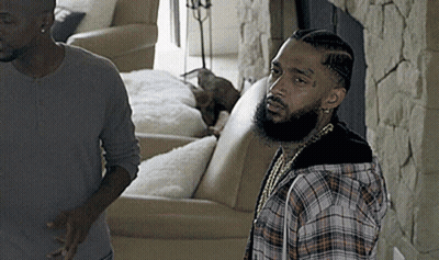 A Man In A Plaid Shirt Stands Next To Another Man In A Living Room GIF