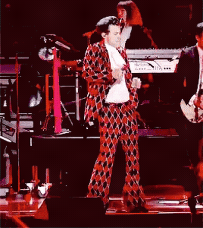 A Man In A Plaid Suit Is Dancing On A Stage GIF