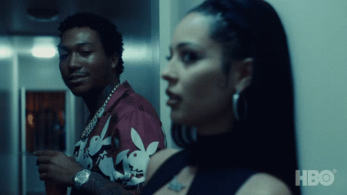 A Man In A Playboy Shirt Is Standing Next To A Woman In A Black Dress GIF