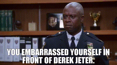 A Man In A Police Uniform And Tie Is Standing In Front Of A Bookshelf And A Trophy . GIF