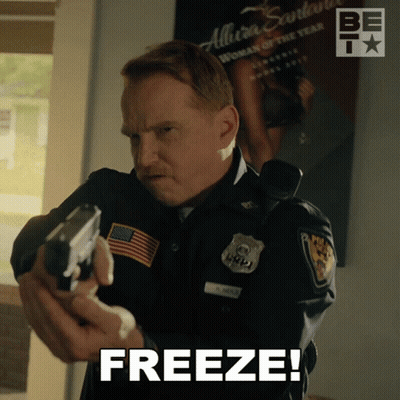 A Man In A Police Uniform Holding A Gun With The Word Freeze Above Him GIF