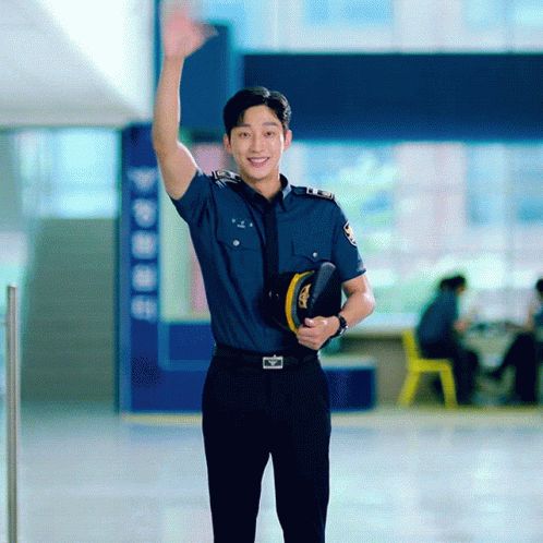 A Man In A Police Uniform Holds A Hat And Waves His Hand GIF