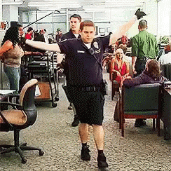 A Man In A Police Uniform Is Dancing In An Office With His Arms Outstretched GIF