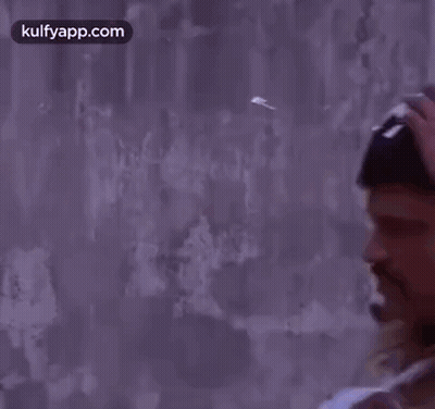 A Man In A Police Uniform Is Holding A Bandaged Arm And A Hat . GIF